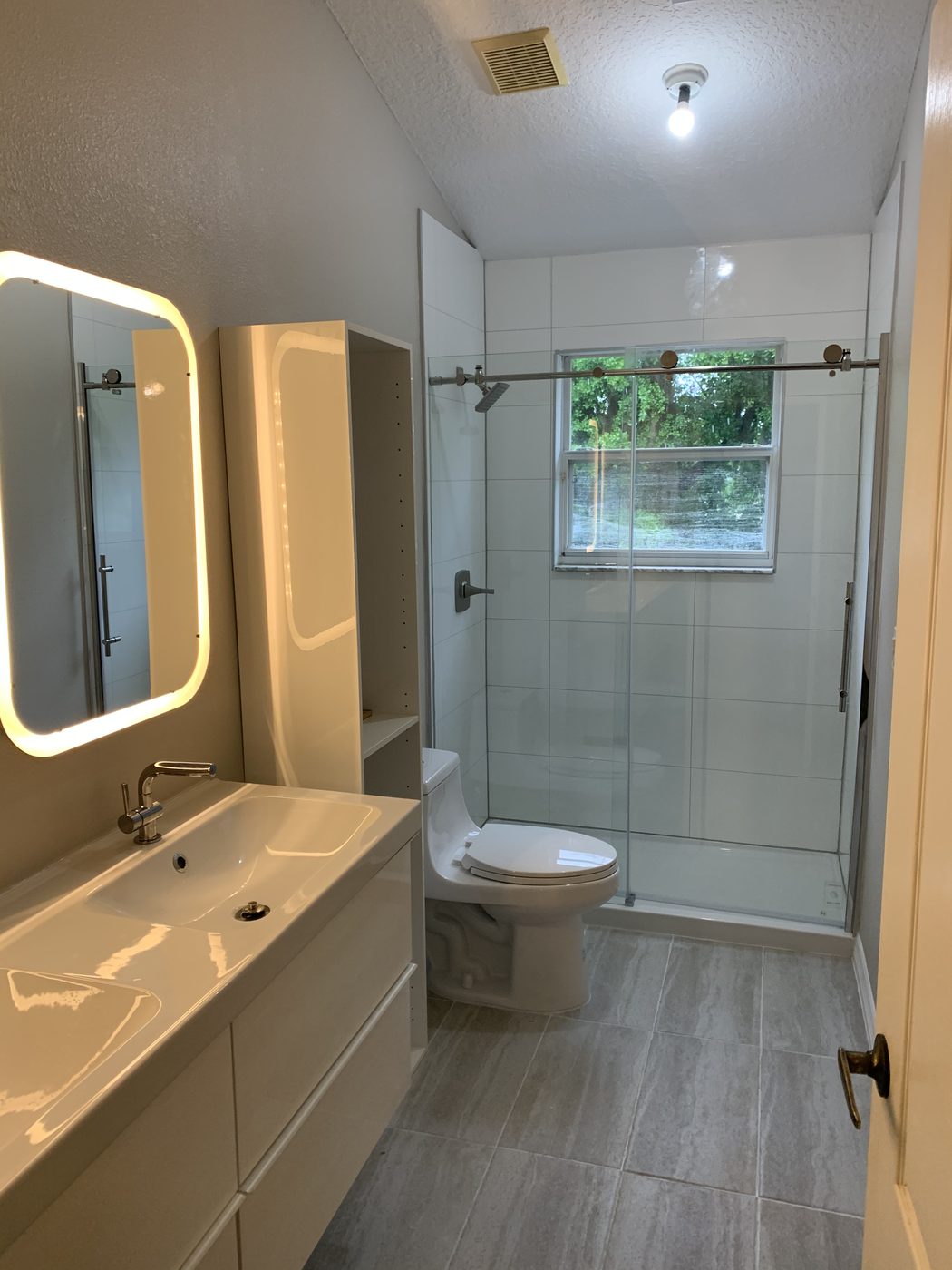 A bright full bathroom with glossy white walls