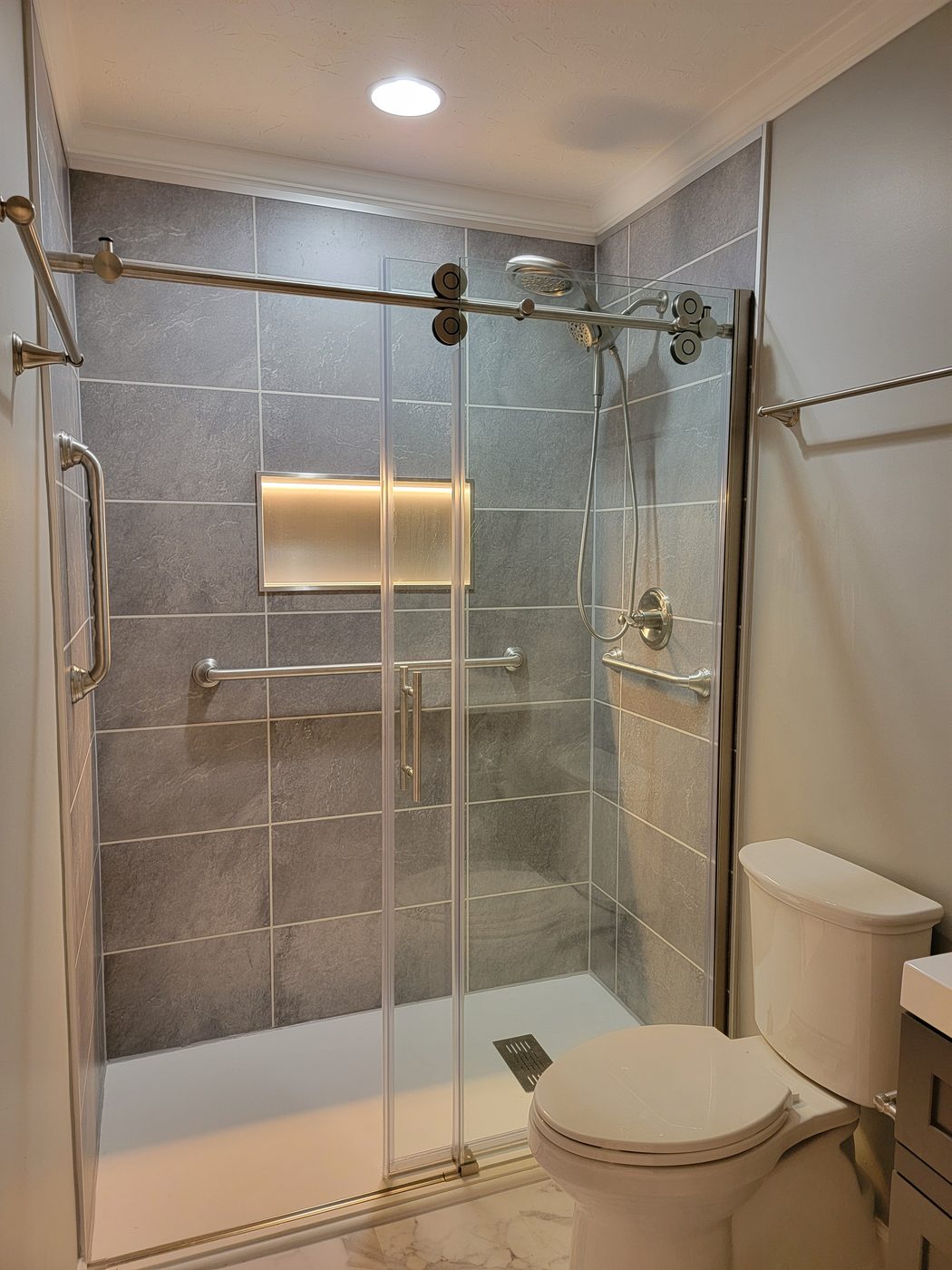 A walk-in shower with grab bars and a built-in bench, built for safe aging in place